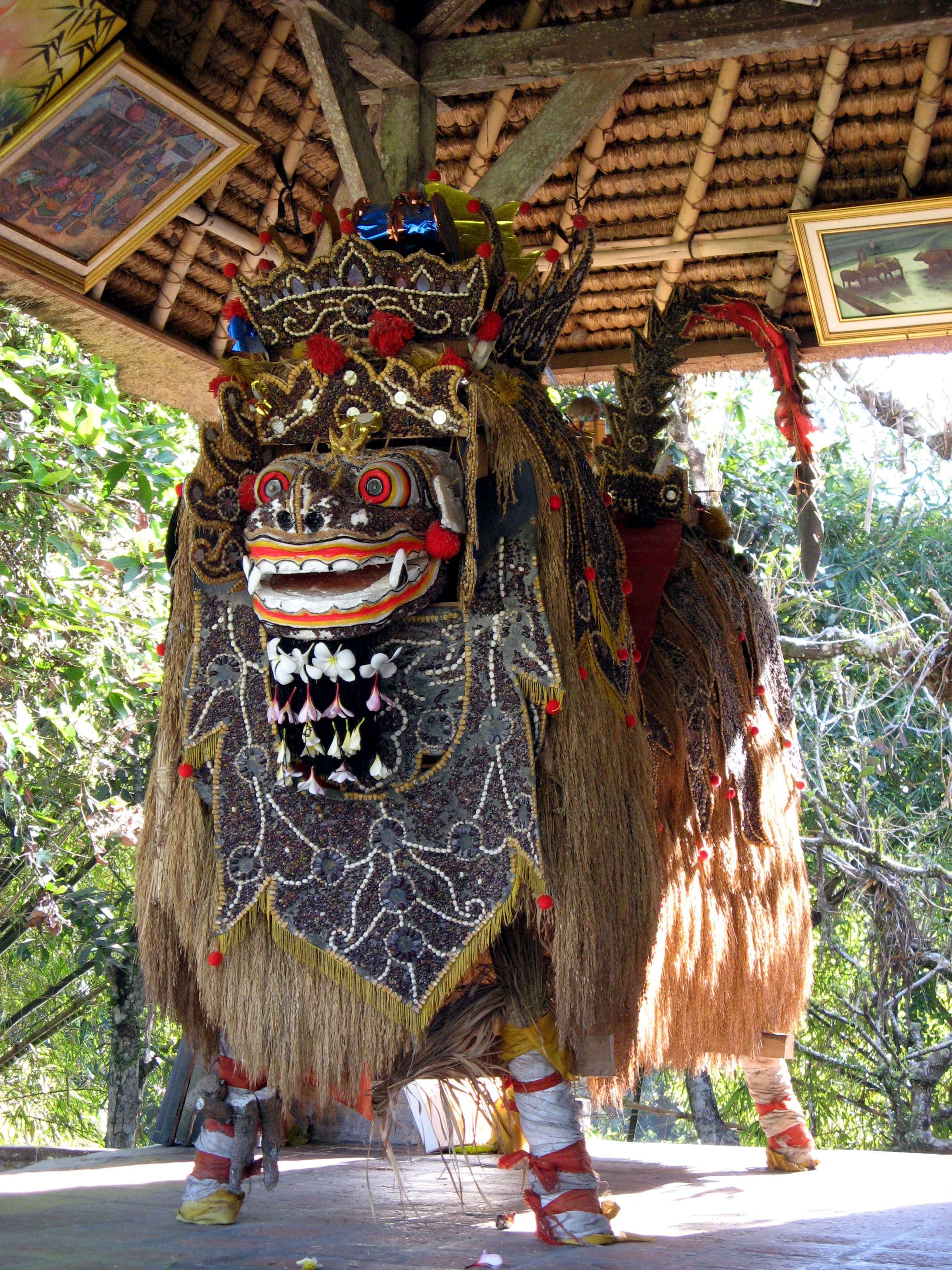 Colorful Balinese Barong mask with golden crown, red face, and elaborate mane of mirror decorations