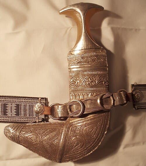 Silver Omani khanjar dagger charm with curved blade and ornate engraved scabbard