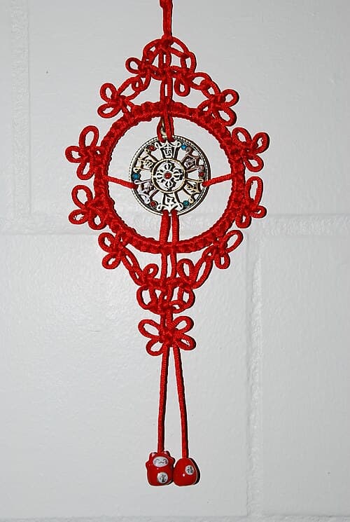 Intricate red and gold Chinese decorative knot with tassel, tied in the classic Pan Chang endless pattern