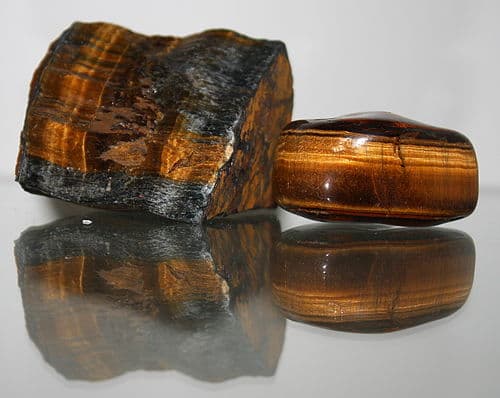 Polished oval tiger's eye stone showing golden chatoyant band moving across rich brown fibrous matrix