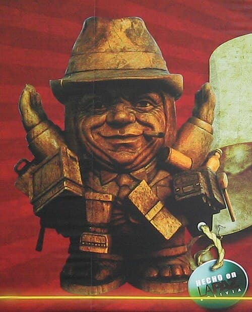 A cheerful Ekeko figure wearing traditional Bolivian dress and loaded with miniature goods including houses, cars, and bags of food