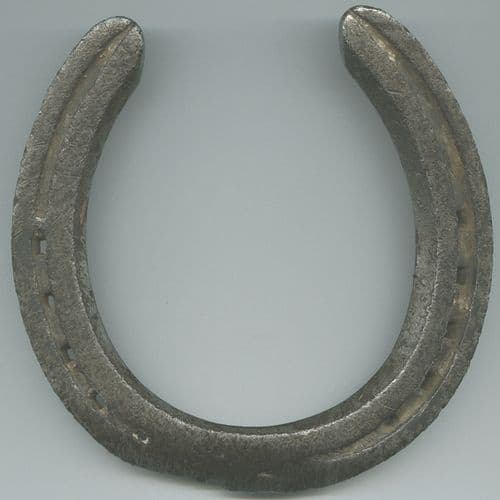 A worn iron horseshoe with seven nail holes against a rustic wooden background