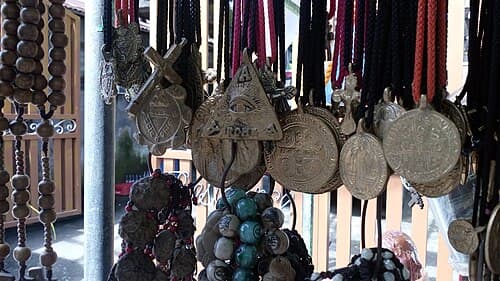 Metal Filipino anting-anting medallion with inscribed Catholic and indigenous symbols on leather cord