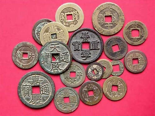 Three ancient-style Chinese bronze coins with square holes, tied together with red thread