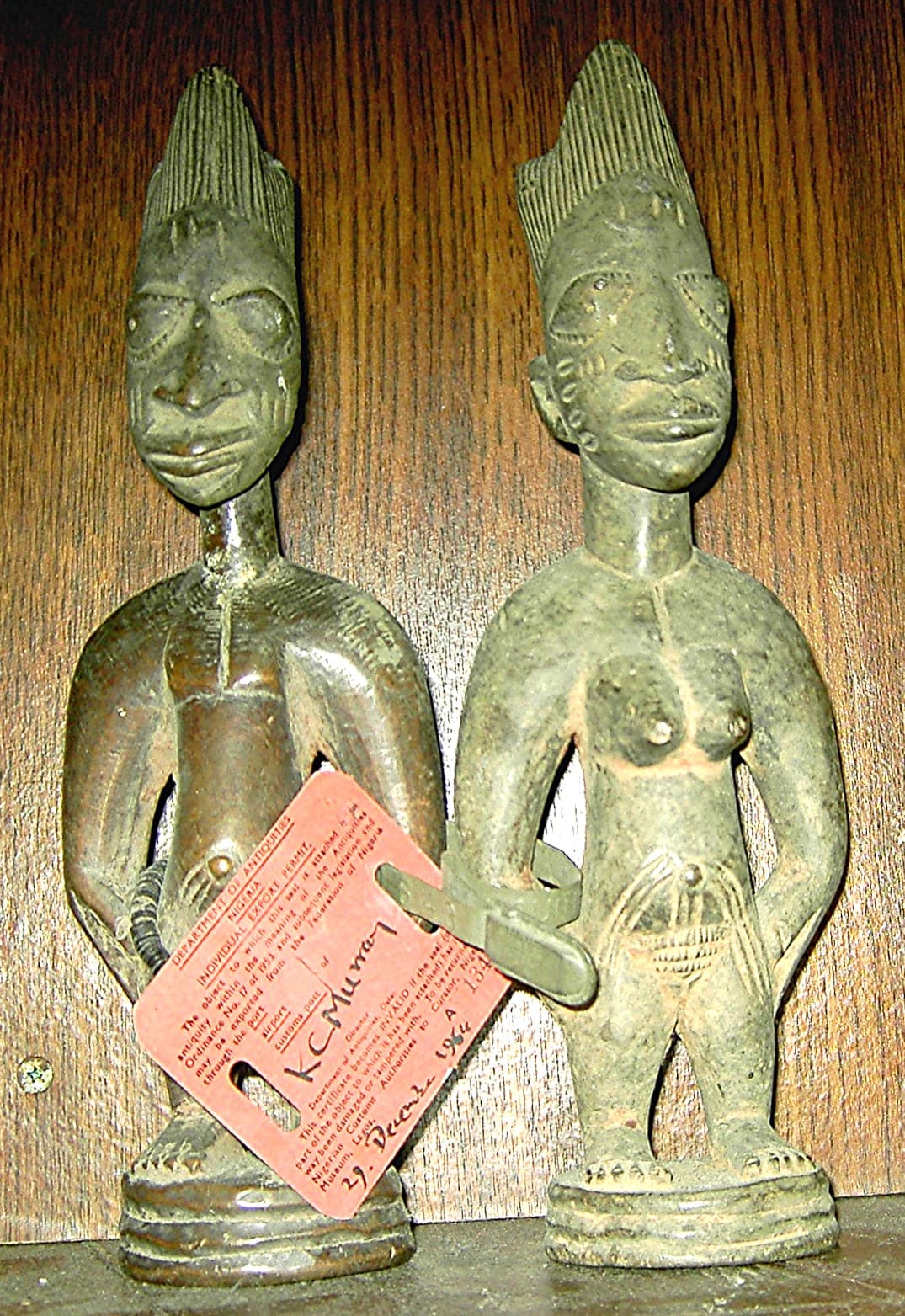 Pair of carved wooden Yoruba ibeji figures adorned with blue indigo and cowrie shell decorations